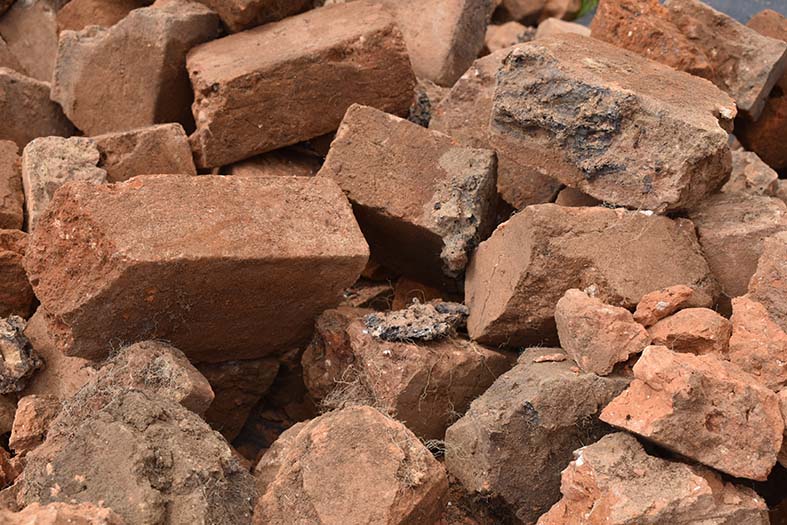 Colour photograph of broken red bricks piled up together.