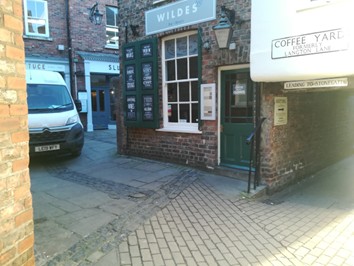 Colour photo of Grape Lane/Coffee Yard junction with alley to left. Brick and paving slab surfaces.