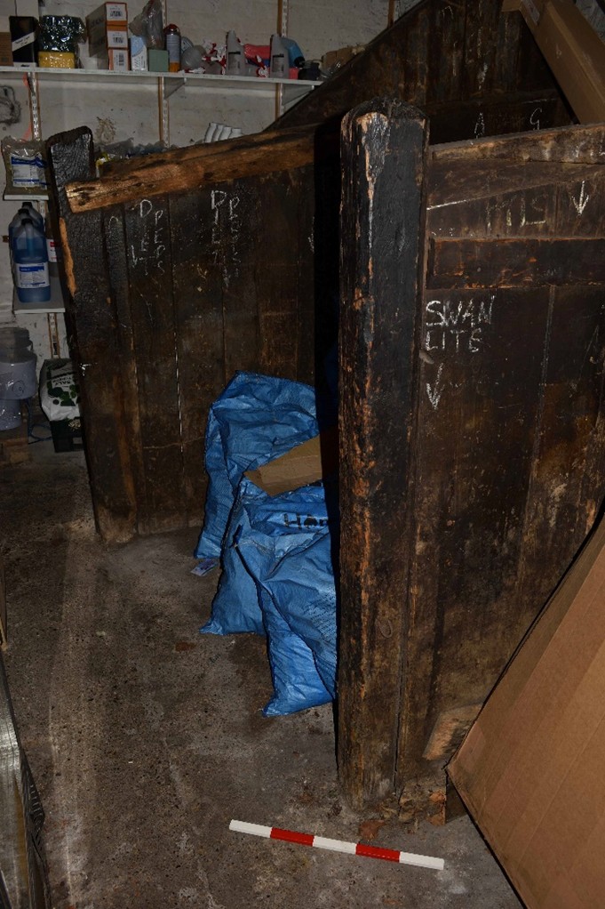 Colour photo of a storage space including timber dividers making stalls for a stables.
