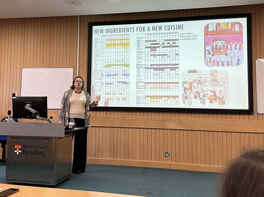 A conference presenter standing in front of a projection screen.