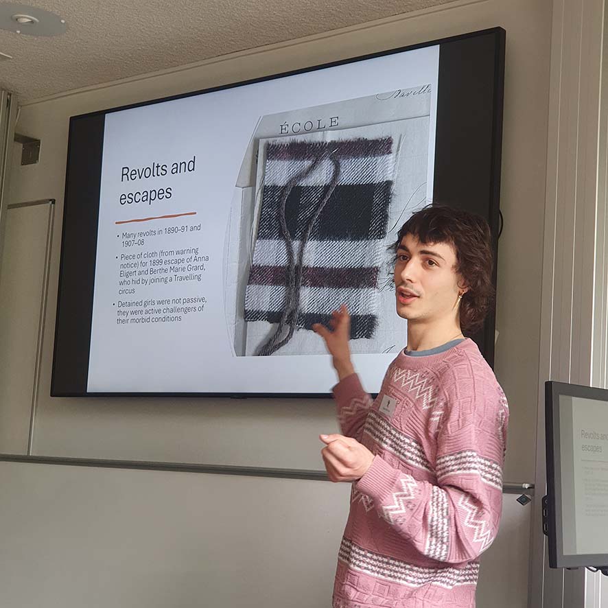 A conference presenter standing in front of a projection screen.