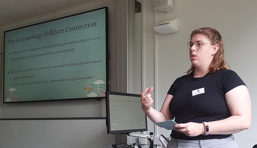 A conference presenter standing in front of a projection screen.