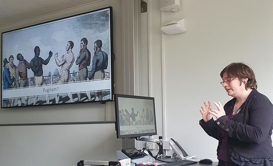 A conference presenter standing in front of a projection screen.