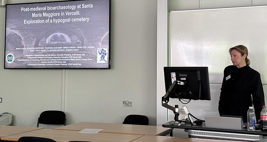 A conference presenter standing in front of a projection screen.