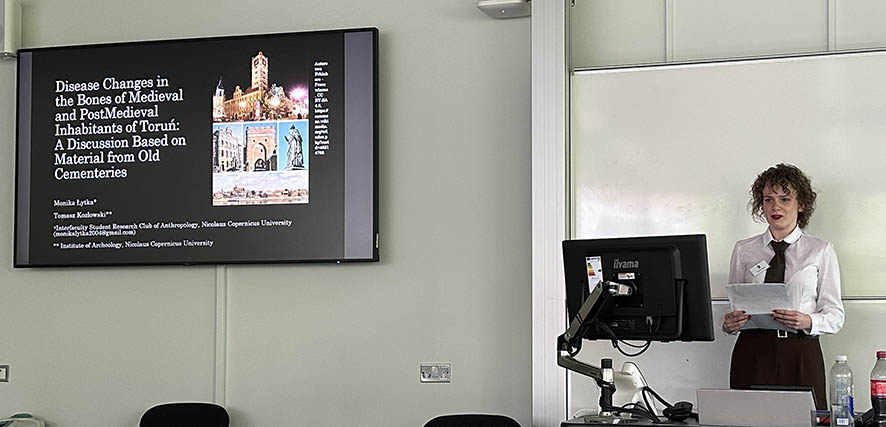 A conference presenter standing in front of a projection screen.