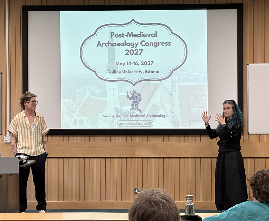 Two conference presenters standing in front of a projection screen.